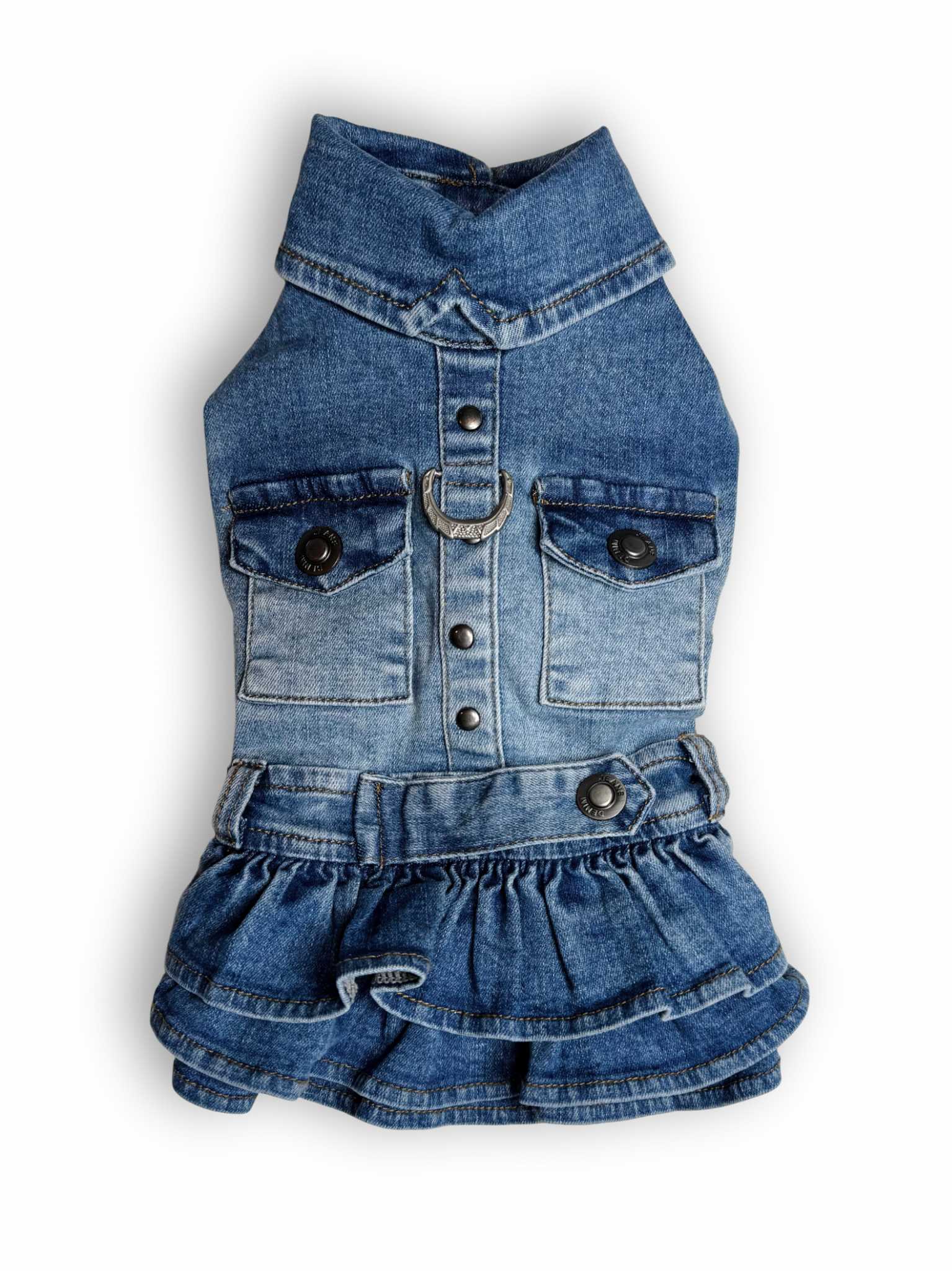 A blue denim dog dress with a ruffled layered skirt, collar neck, and sleeveless design. It includes two non-functional pockets and a D-ring for leash attachment.